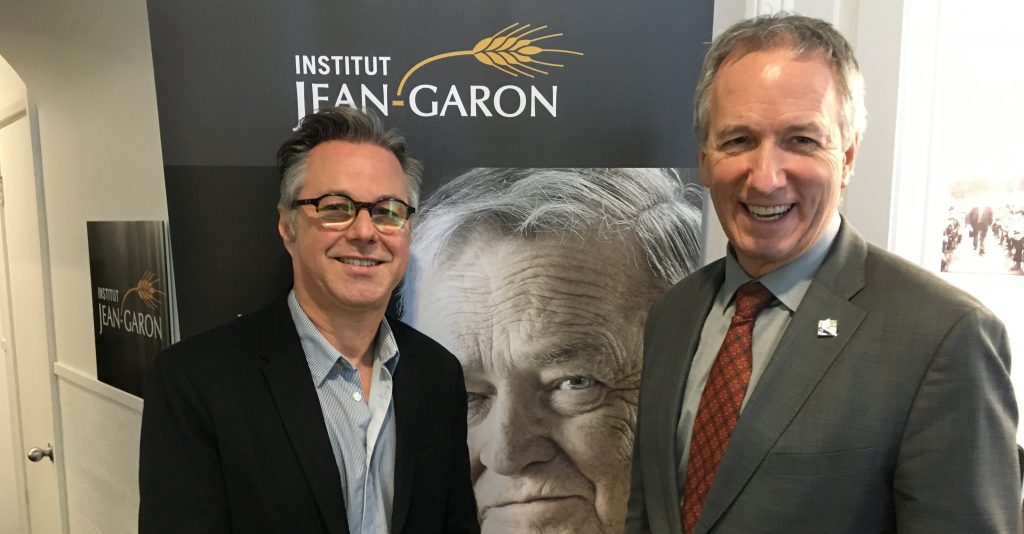 André Lamontagne, ministre de l’Agriculture du Québec, et Yannick Patelli, éditeur de La Vie agricole entourant le portrait de Jean Garon qui trône dans le hall d’entrée de la Maison blanche à Québec.